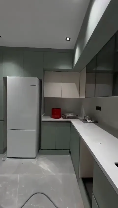 Sage green galley kitchen with white stone worktops and full-height cabinets